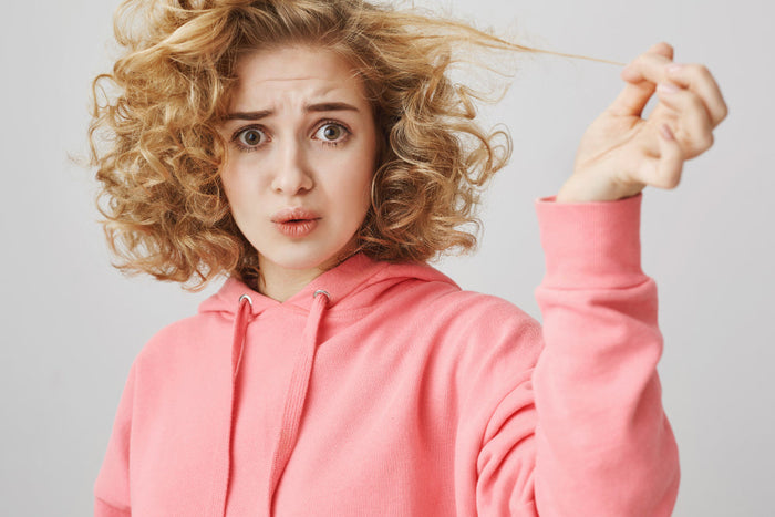 Woman with curly hair confused—learn how to get rid of split ends curly hair and protect natural curls from damage.