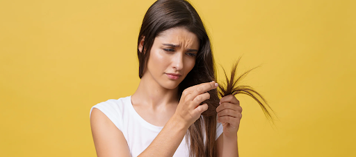 Woman checking her hair for early signs of split ends—spotting damage before it becomes dead ends.