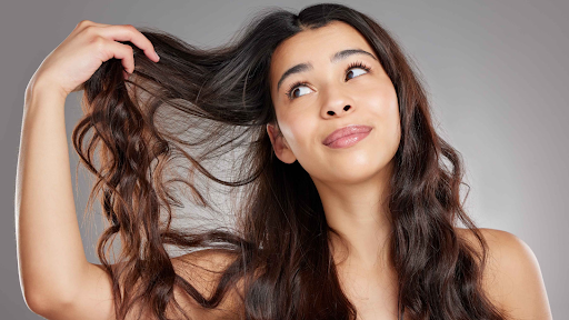 Woman examining her hair ends for signs of damage—early check for split ends treatment and length preservation.